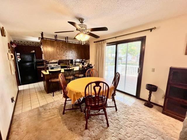 dining space featuring a textured ceiling, light tile patterned floors, and ceiling fan