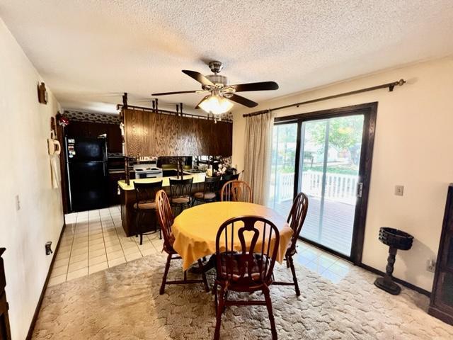 dining area featuring a textured ceiling, light tile patterned floors, and ceiling fan