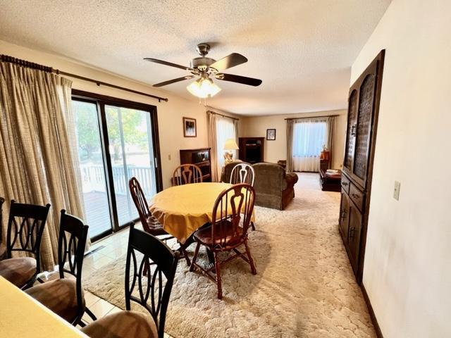 carpeted dining area featuring a textured ceiling and ceiling fan