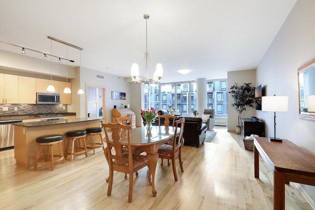 dining room with visible vents, light wood-style flooring, and a notable chandelier