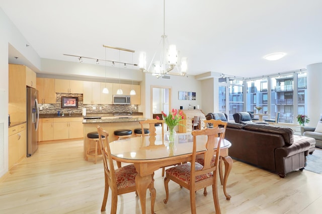 dining area with light wood finished floors and a notable chandelier