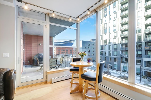 sunroom with a baseboard heating unit and a city view