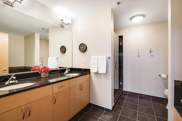 bathroom with double vanity, a sink, toilet, and tile patterned floors