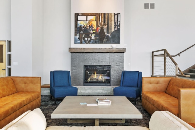 living area with stairway, a glass covered fireplace, and visible vents