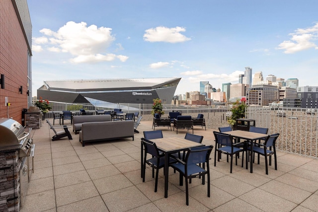 view of patio / terrace featuring outdoor dining area, a city view, grilling area, an outdoor kitchen, and an outdoor hangout area