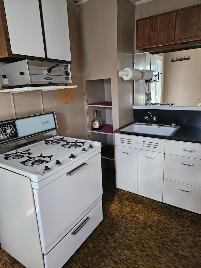 kitchen with white range, ventilation hood, sink, and white cabinets