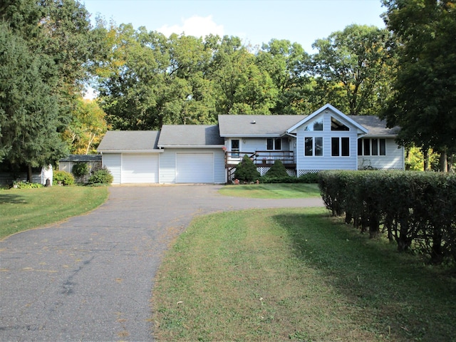 ranch-style house with a deck, a front yard, and a garage