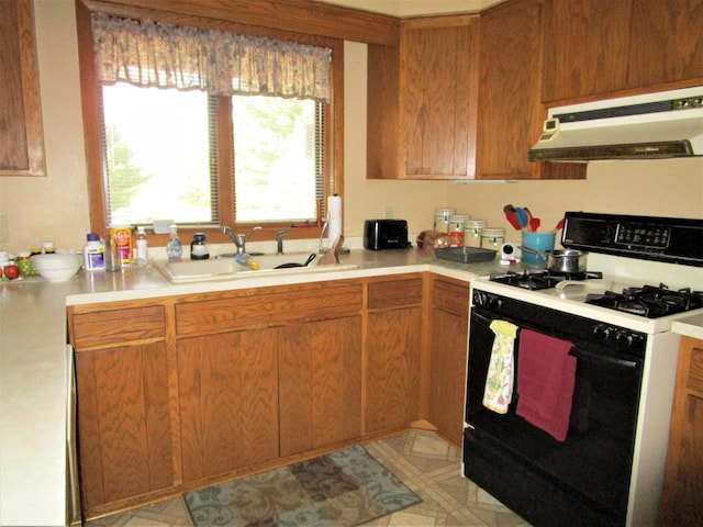 kitchen with white range with gas stovetop, sink, and exhaust hood