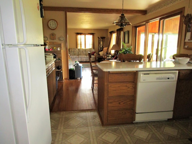 kitchen featuring kitchen peninsula, white appliances, and hanging light fixtures