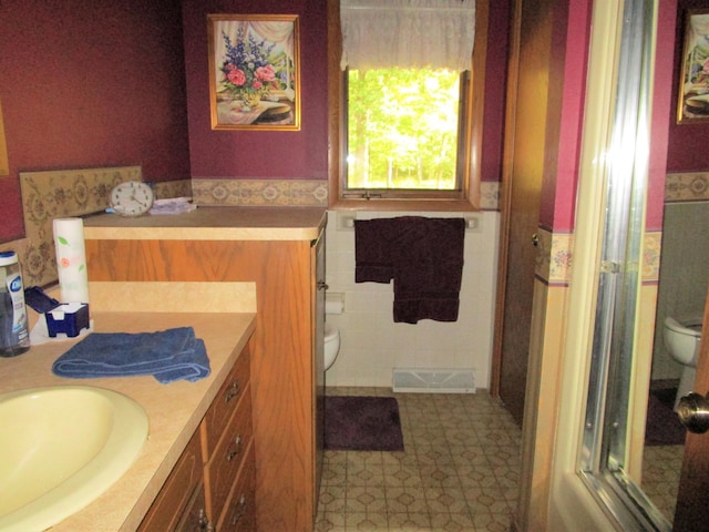 bathroom with vanity, toilet, and tile walls