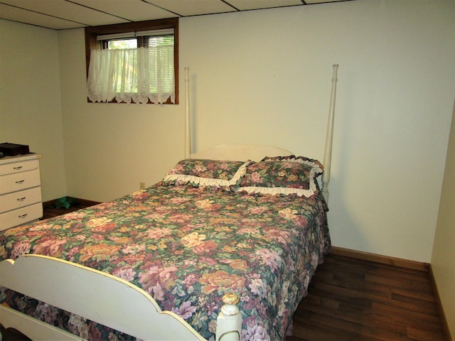 bedroom with a paneled ceiling and dark hardwood / wood-style floors