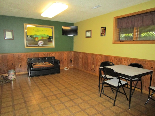 dining area featuring a textured ceiling and wooden walls