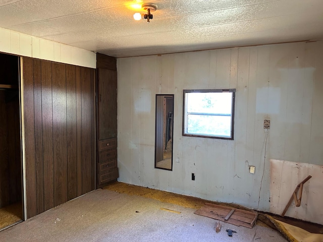 carpeted spare room with wood walls