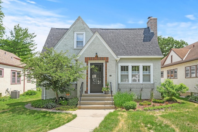 tudor home featuring central AC and a front lawn