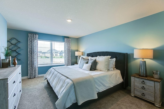 bedroom with a textured ceiling and dark colored carpet