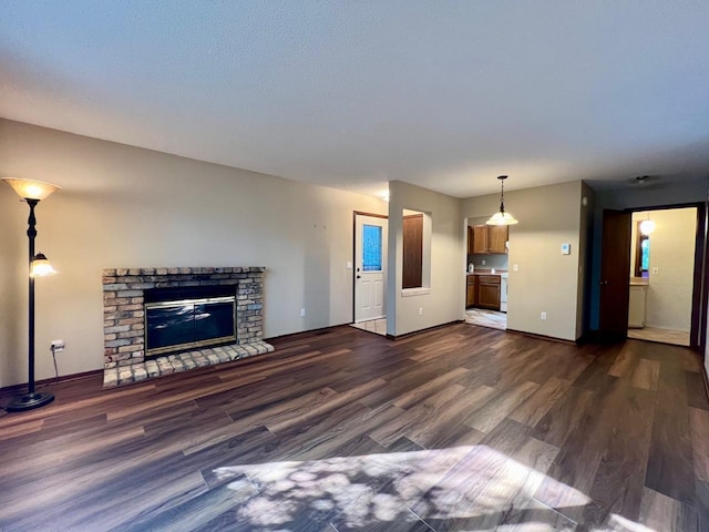 unfurnished living room featuring dark wood-type flooring and a brick fireplace