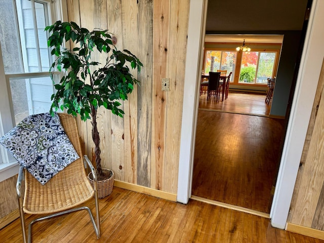 corridor featuring wooden walls, hardwood / wood-style flooring, and an inviting chandelier