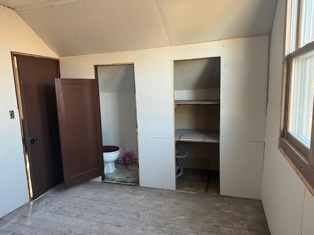 unfurnished bedroom featuring ensuite bath and vaulted ceiling