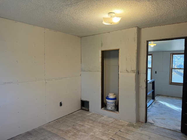 empty room with light hardwood / wood-style floors and a textured ceiling