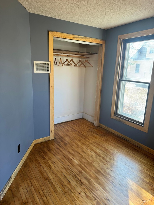 unfurnished bedroom featuring a closet, hardwood / wood-style floors, and a textured ceiling