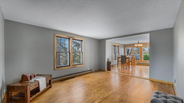 interior space with a notable chandelier, hardwood / wood-style flooring, a textured ceiling, and a baseboard radiator