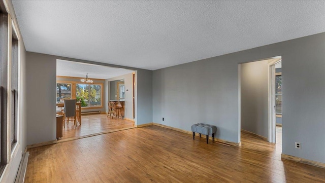 unfurnished living room featuring a notable chandelier, wood-type flooring, and a textured ceiling