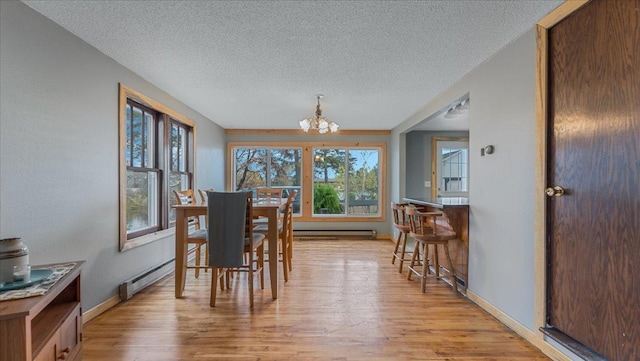 dining space featuring a chandelier, a textured ceiling, a baseboard radiator, and light wood-type flooring