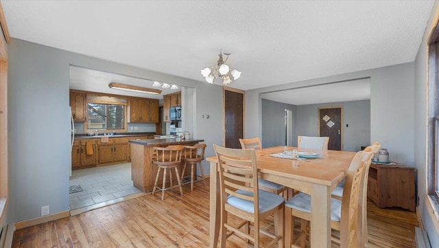 dining room with an inviting chandelier, a textured ceiling, and light wood-type flooring