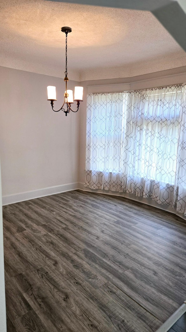 unfurnished room featuring a wealth of natural light, a textured ceiling, and dark hardwood / wood-style flooring