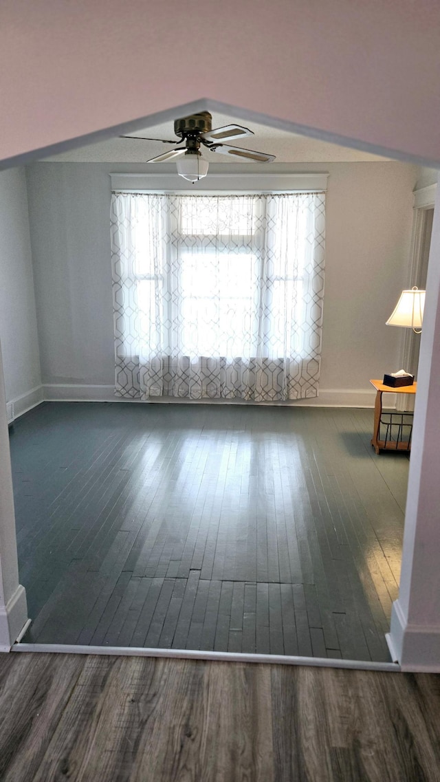 empty room with dark hardwood / wood-style flooring and ceiling fan