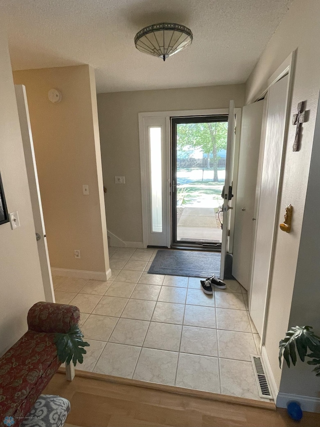 foyer entrance with light tile patterned floors and a textured ceiling