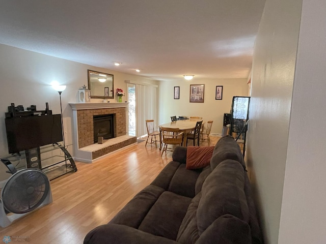 living room with light hardwood / wood-style floors and a brick fireplace