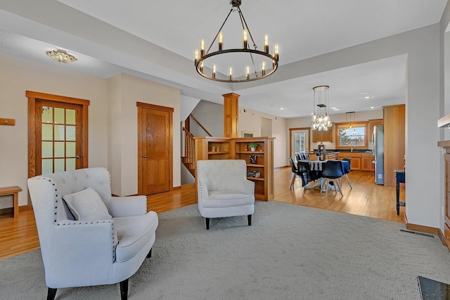 2008 11th St N, Sartell, MN 56377 - living area with a chandelier, light wood-type flooring, decorative columns, stairs, and light colored carpet