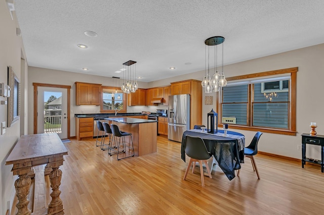 2008 11th St N, Sartell, MN 56377 - kitchen featuring appliances with stainless steel finishes, dark countertops, light wood-type flooring, a textured ceiling, and a center island