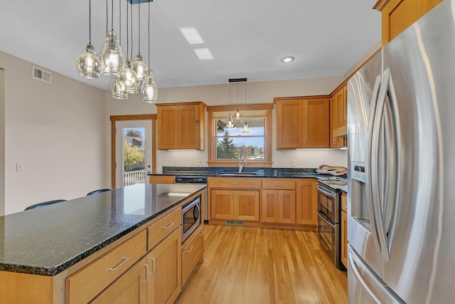 2008 11th St N, Sartell, MN 56377 - kitchen featuring stainless steel appliances, light wood-type flooring, a kitchen island, decorative light fixtures, and a chandelier