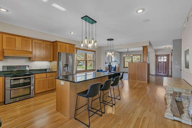 2008 11th St N, Sartell, MN 56377 - kitchen with appliances with stainless steel finishes, under cabinet range hood, dark countertops, a breakfast bar, and light wood finished floors