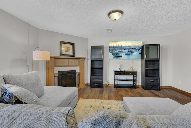 2008 11th St N, Sartell, MN 56377 - living room featuring dark wood-style flooring, baseboards, a textured ceiling, and a glass covered fireplace