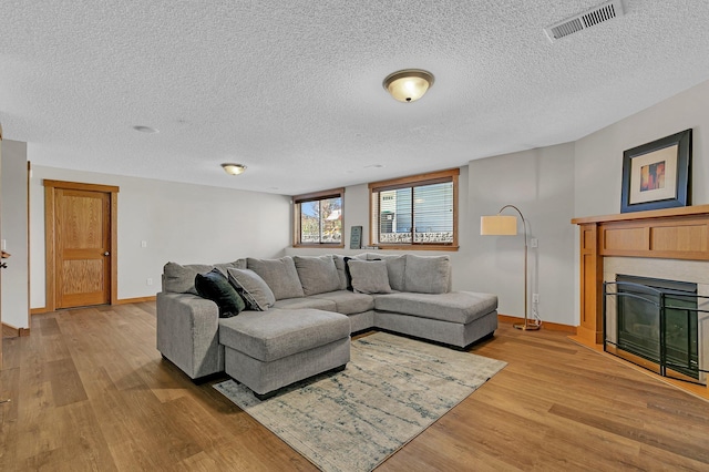2008 11th St N, Sartell, MN 56377 - living area featuring a glass covered fireplace, light wood-style floors, baseboards, and a textured ceiling