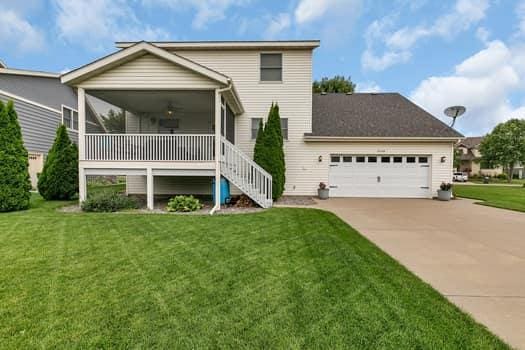 2008 11th St N, Sartell, MN 56377 - view of front of home featuring driveway, a front lawn, an attached garage, and stairway