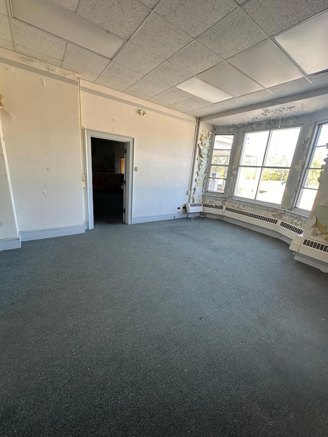 carpeted empty room with a baseboard radiator and a paneled ceiling