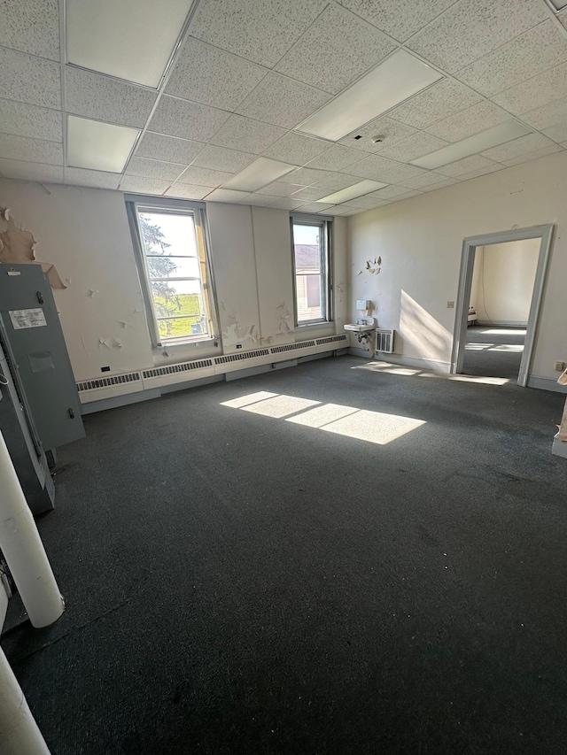 carpeted empty room featuring baseboard heating and a paneled ceiling