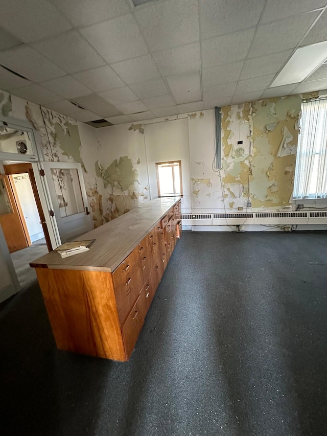 interior space with a baseboard heating unit, a healthy amount of sunlight, and a paneled ceiling