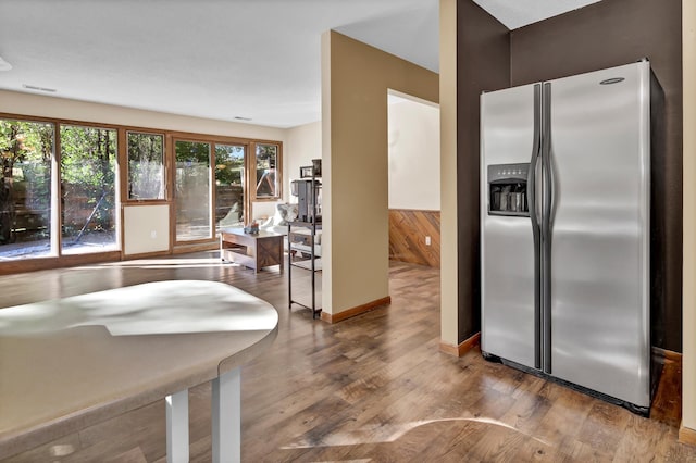 kitchen with stainless steel fridge, wooden walls, and hardwood / wood-style floors