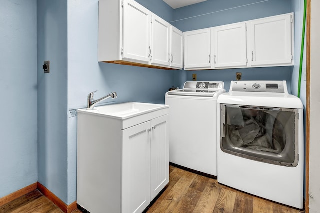 washroom with washing machine and clothes dryer, dark hardwood / wood-style floors, cabinets, and sink