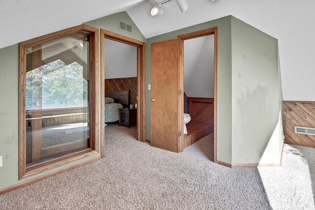 interior space with light colored carpet, wooden walls, and lofted ceiling