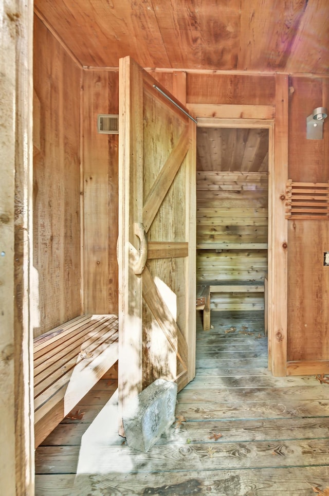 interior space featuring wooden ceiling, wood-type flooring, and wood walls