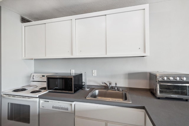 kitchen featuring white appliances, white cabinets, sink, and a textured ceiling