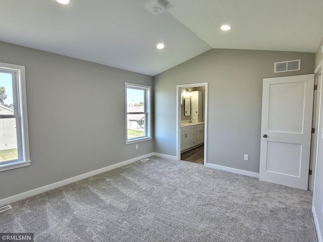 unfurnished bedroom featuring lofted ceiling, carpet flooring, and connected bathroom