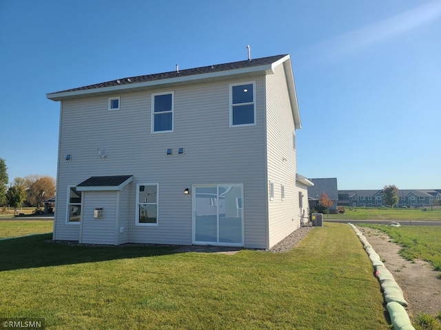 rear view of property featuring a lawn and central AC