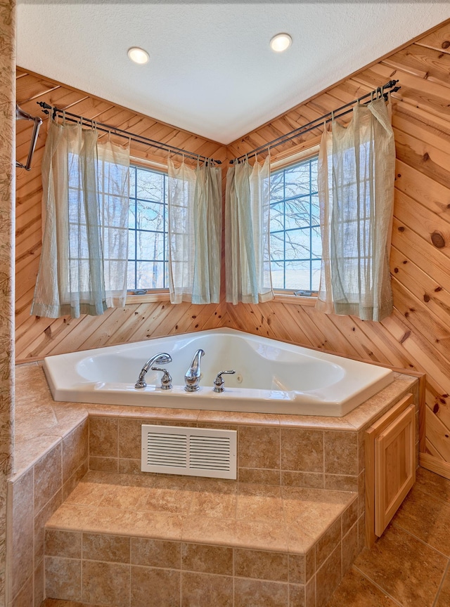 bathroom with wooden walls, tile patterned floors, a bath, and a wealth of natural light